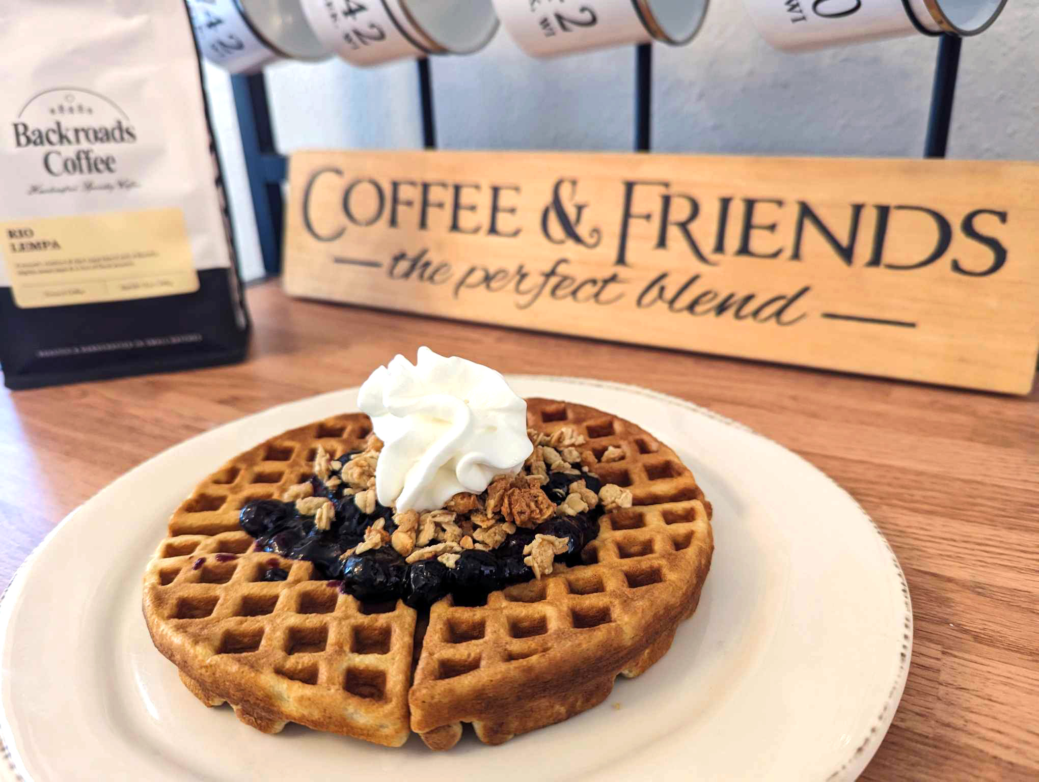 Waffle topped with blueberry sauce, granola, and whipped cream